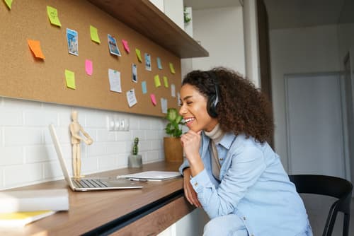 A woman wearing headphones smiling during a video coaching session at her desk